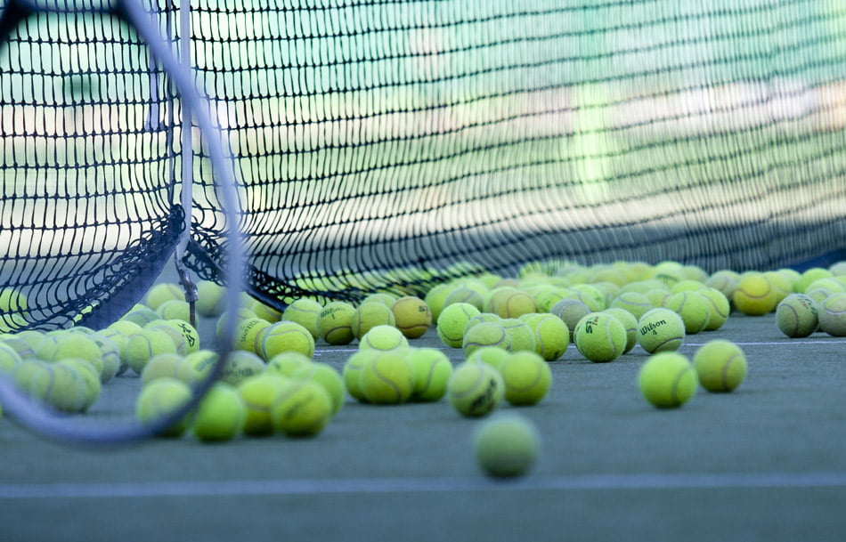 A large amount of tennis balls on a tennis court