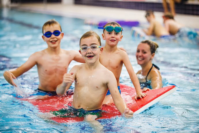 three children in the swimming pool smiling