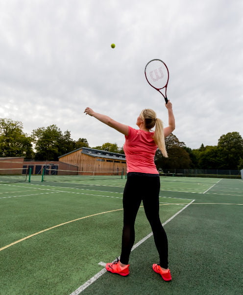 Woman plaging a game of tennis on one of the outdoor pitches