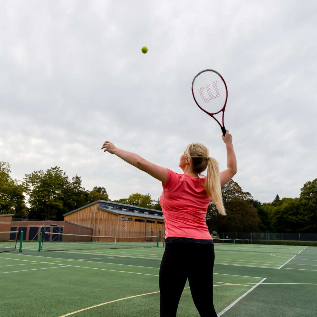 Woman plaging a game of tennis on one of the outdoor pitches