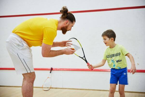 squash coach teaching young child