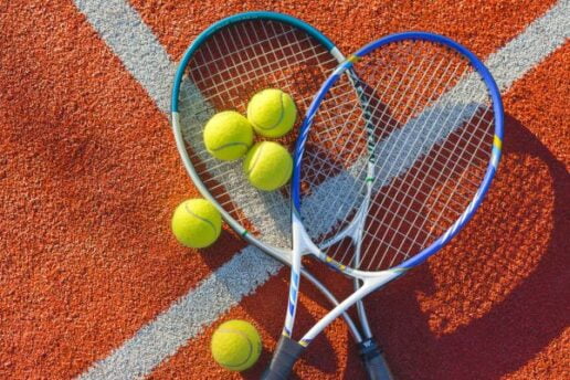 2 tennis rackets with 5 tennis balls on top of them