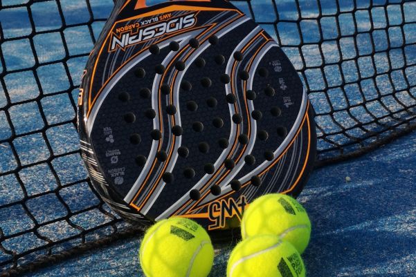 a padel racket with 3 tennis balls