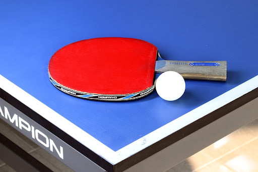 a table tennis bat and ping pong ball on a table tennis table