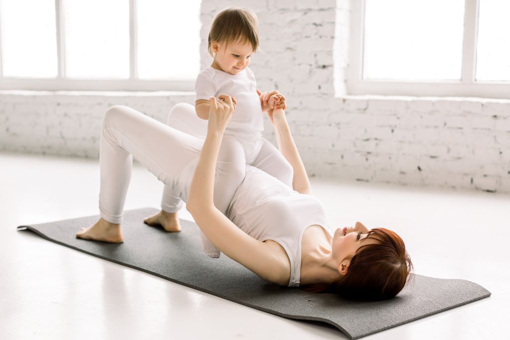 Mother with her child on top of her on an exercise mat