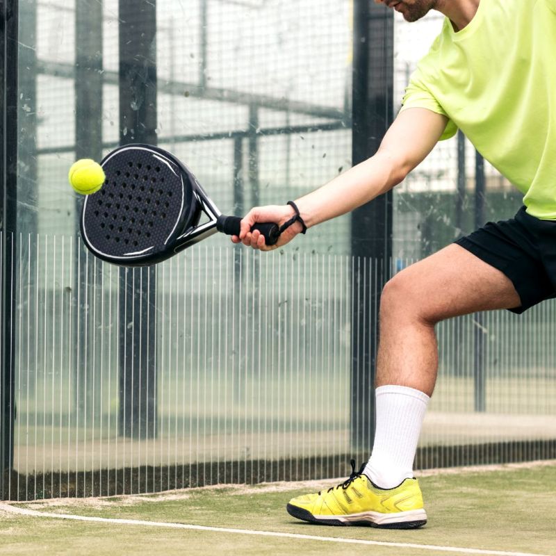 man hitting a ball with a padel racket on a padel court