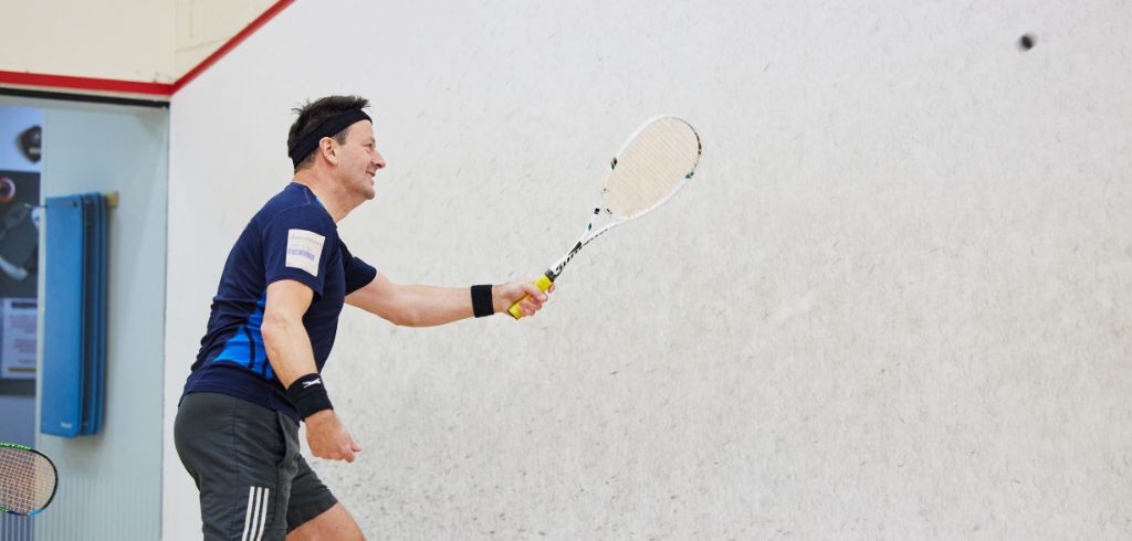 man hitting a squash ball