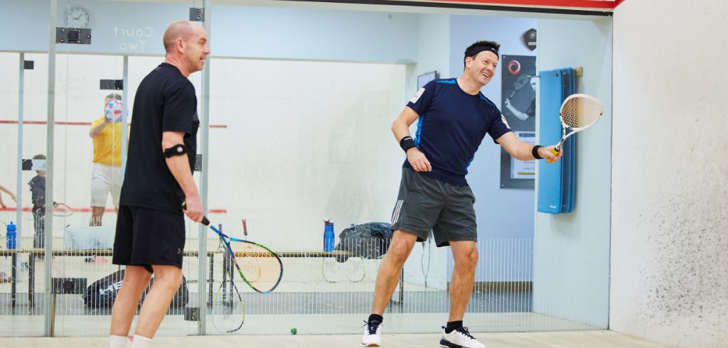 two men playing squash and smiling