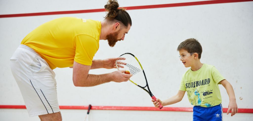 squash coach teaching a child squash