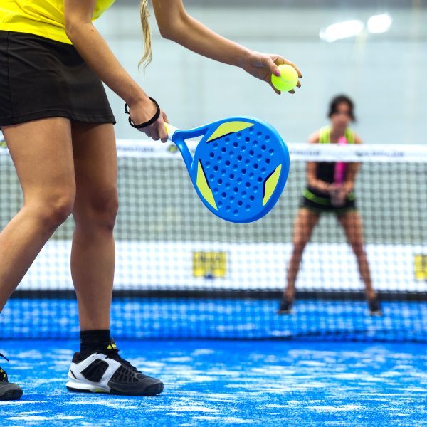 Someone serving in a padel game