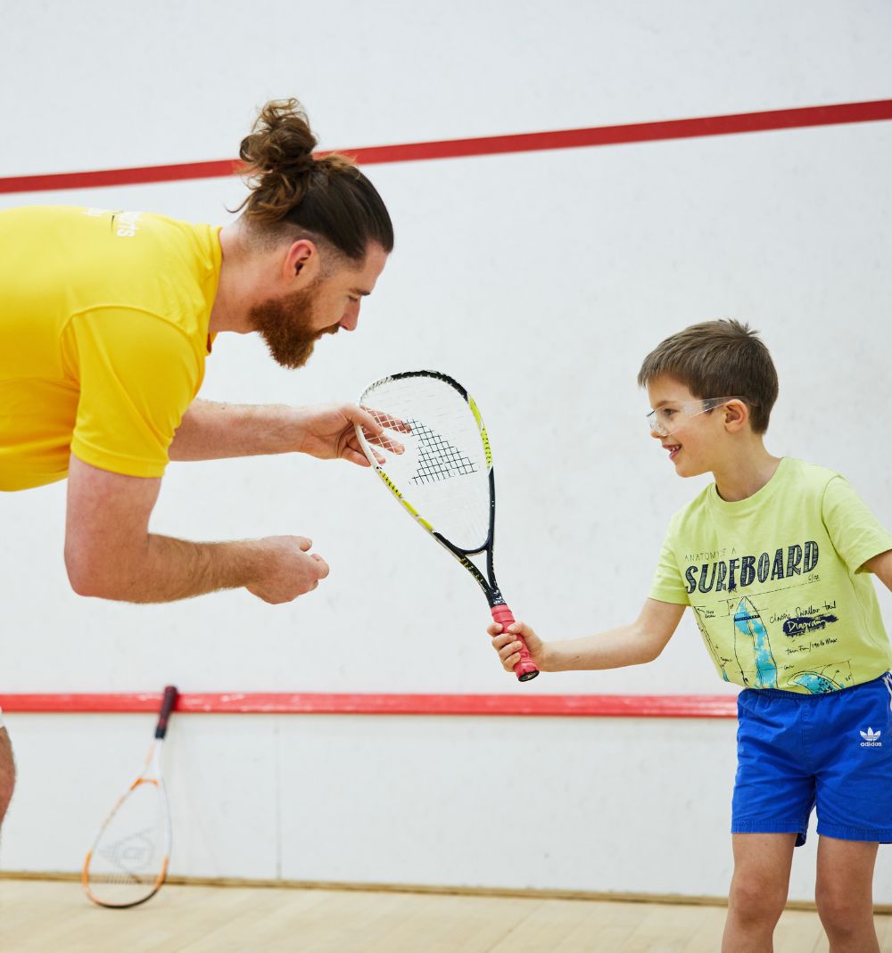 Squash coach teaching a child