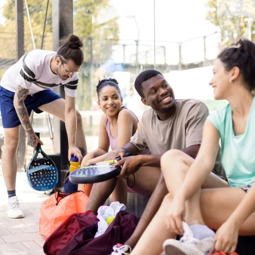 group of friends sitting on padel court sidelines