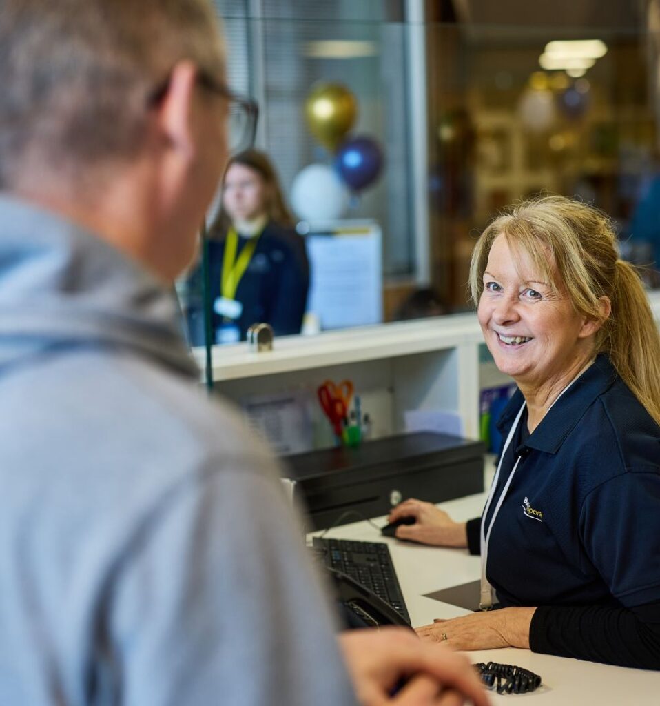 Bluecoat Sports reception staff member interacting with customer smiling