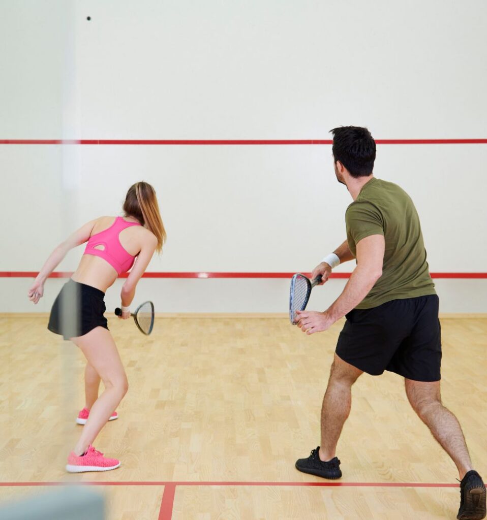 man and woman playing squash in indoor court