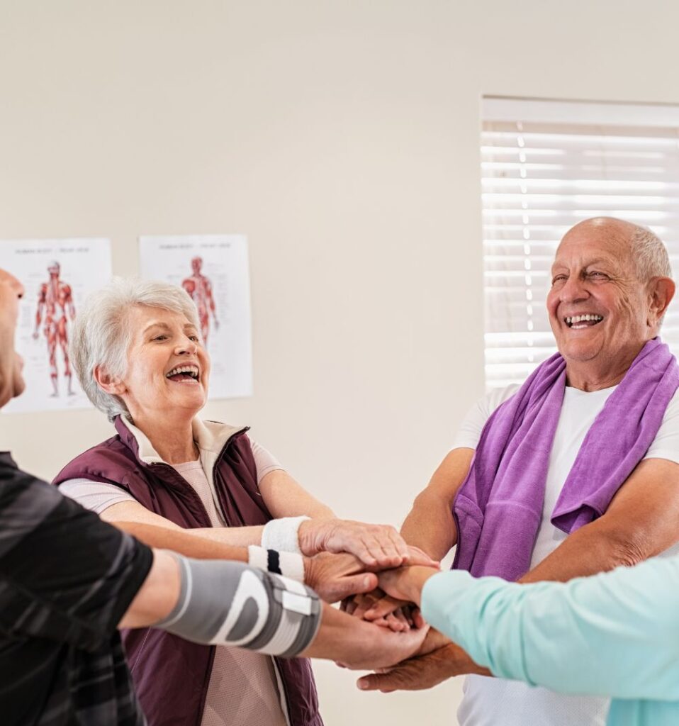Senior fitness group with their hands together smiling