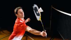 man hitting a shuttlecock playing badminton