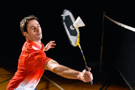 man hitting a shuttlecock playing badminton
