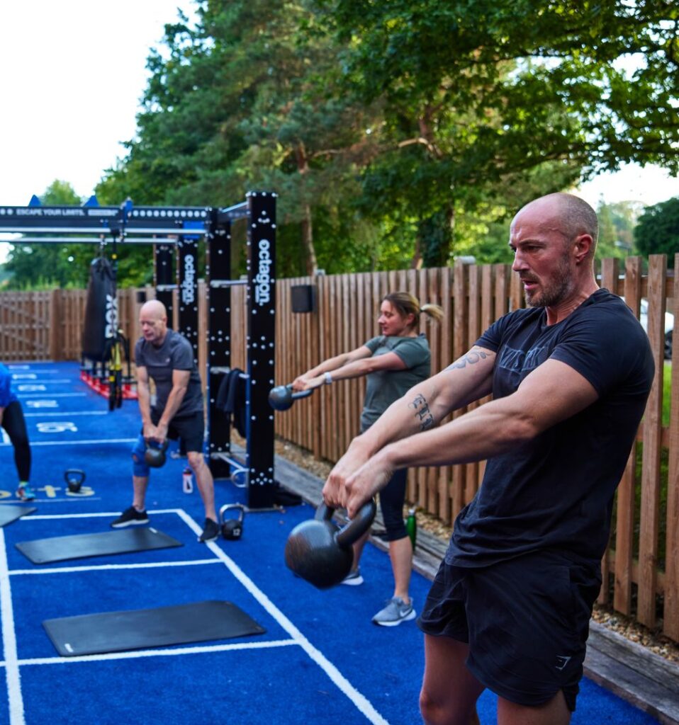 men and women doing kettlebell swings in outdoor fitness yard