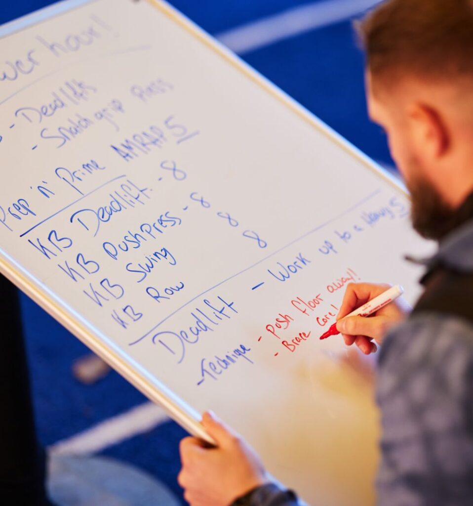 personal trainer planning workout on whiteboard