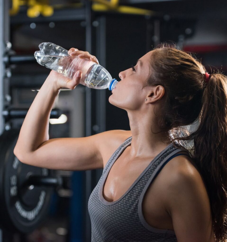 woman drinking water during workout in the gym