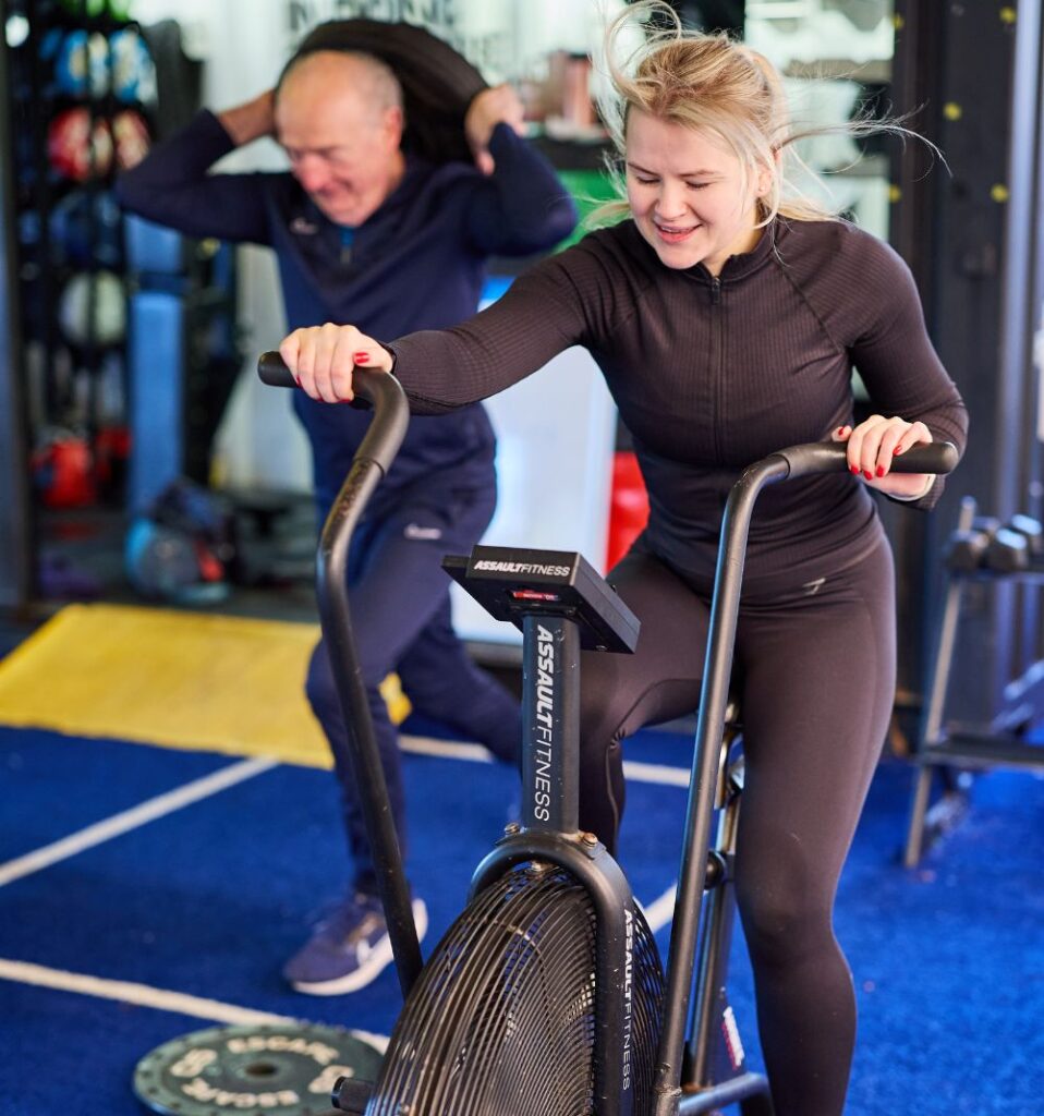 woman exercising on air bike in bluecoat sports outdoor gym