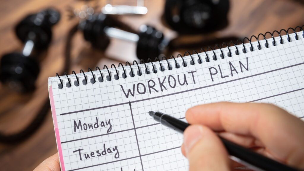 person holding notebook writing out workout plan
