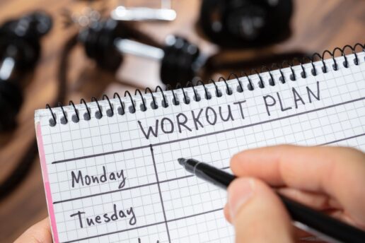 person holding notebook writing out workout plan