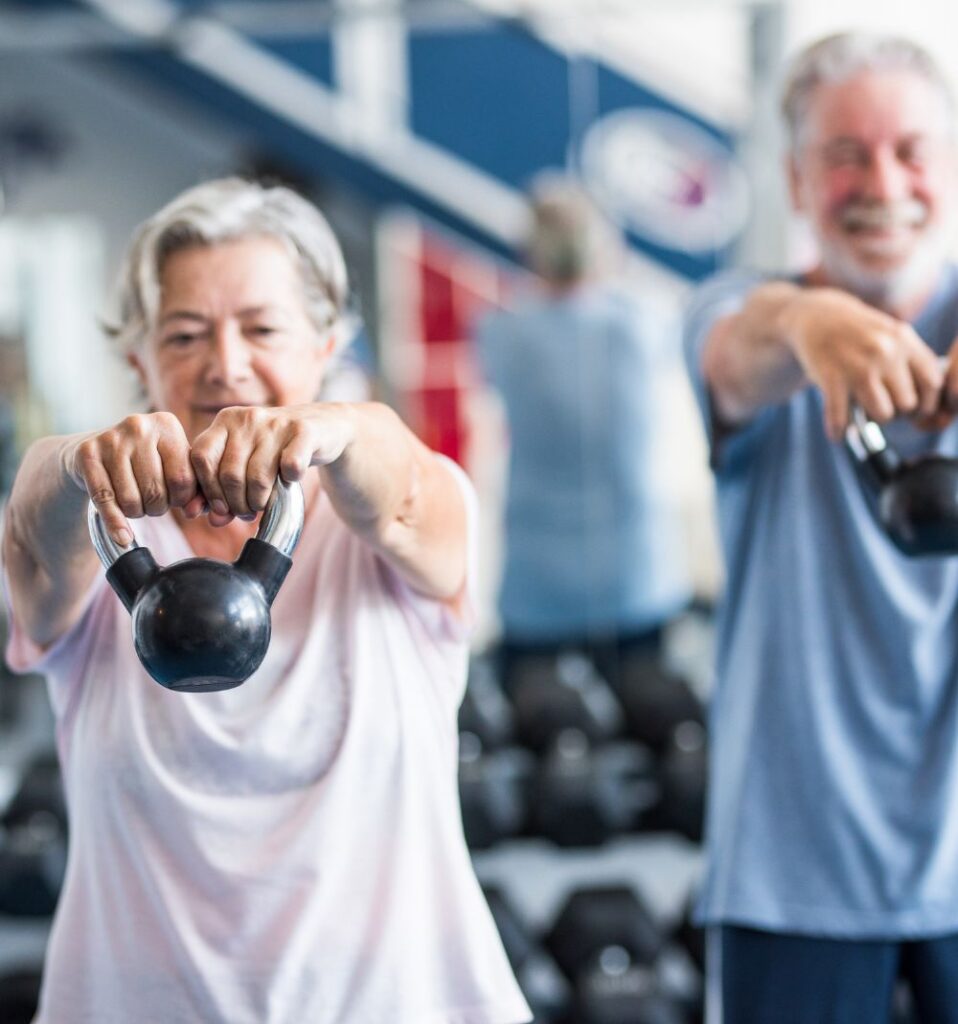 senior man and woman using kettlebells in a gym
