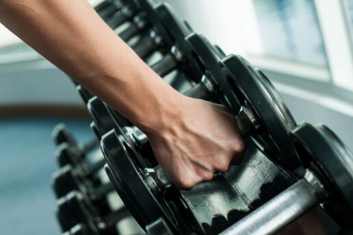 person picking up dumbbells from dumbbell rack