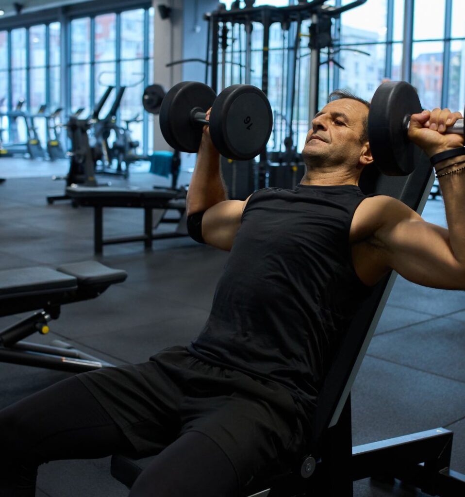 man doing a dumbbell press in the gym