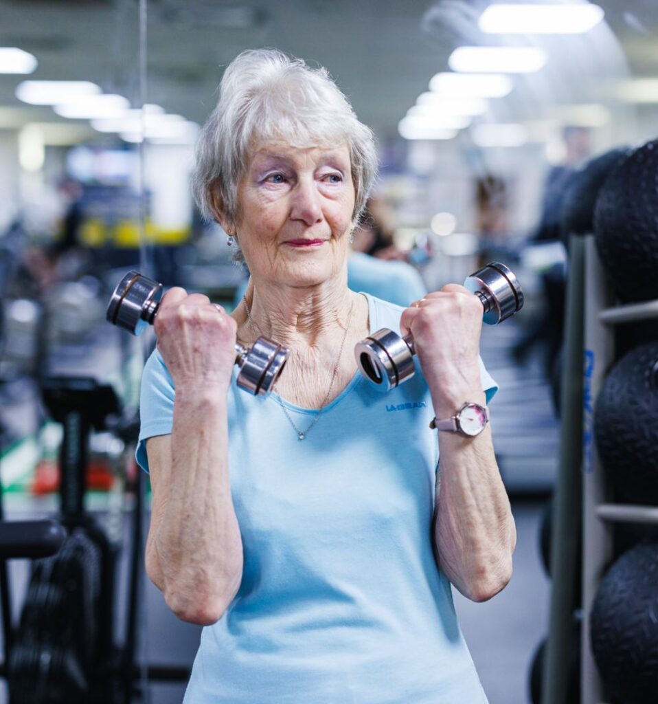 senior woman working out with dumbbells in gym