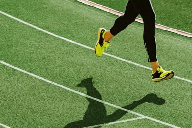 person running on athletics track with shadow