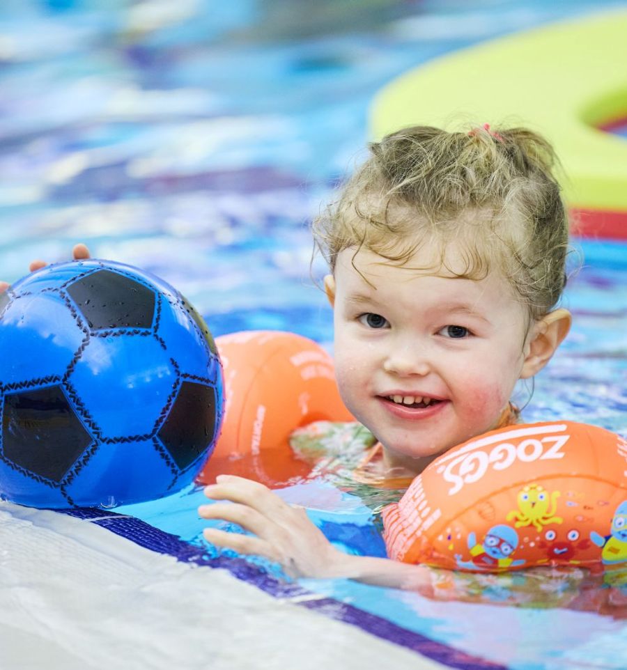 young girl in swimming pool playing with a ball