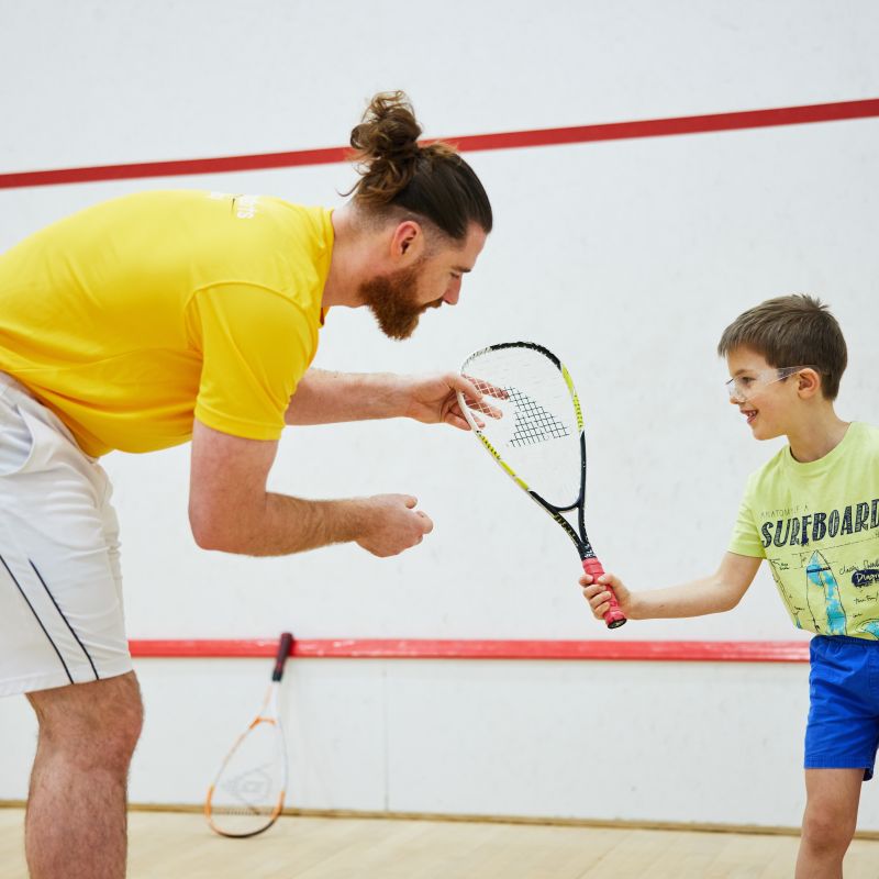 squash coach Kit teaching a junior squash