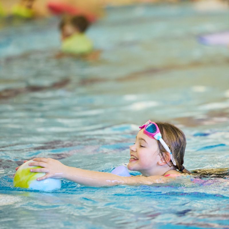 child in swimming pool with pool noodle and inflatable ball