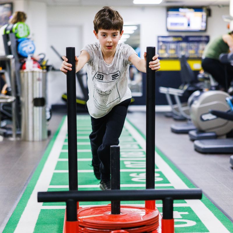 young boy doing a sled push in the bluecoat sports fitness suite