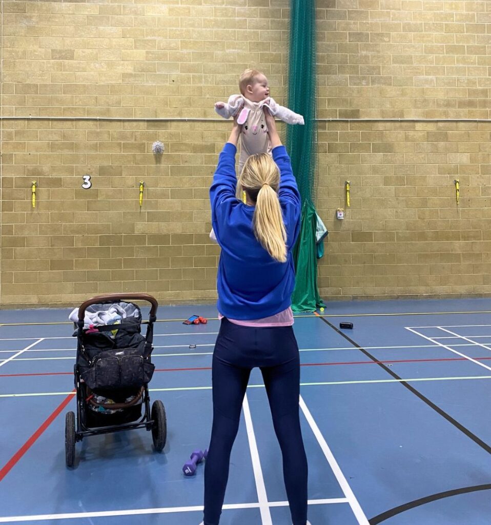 woman lifting baby in exercise class