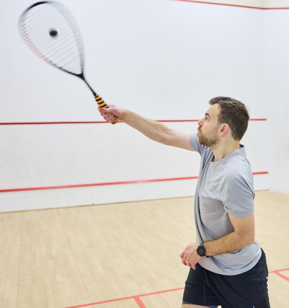 man in a squash court hitting the ball with a racket